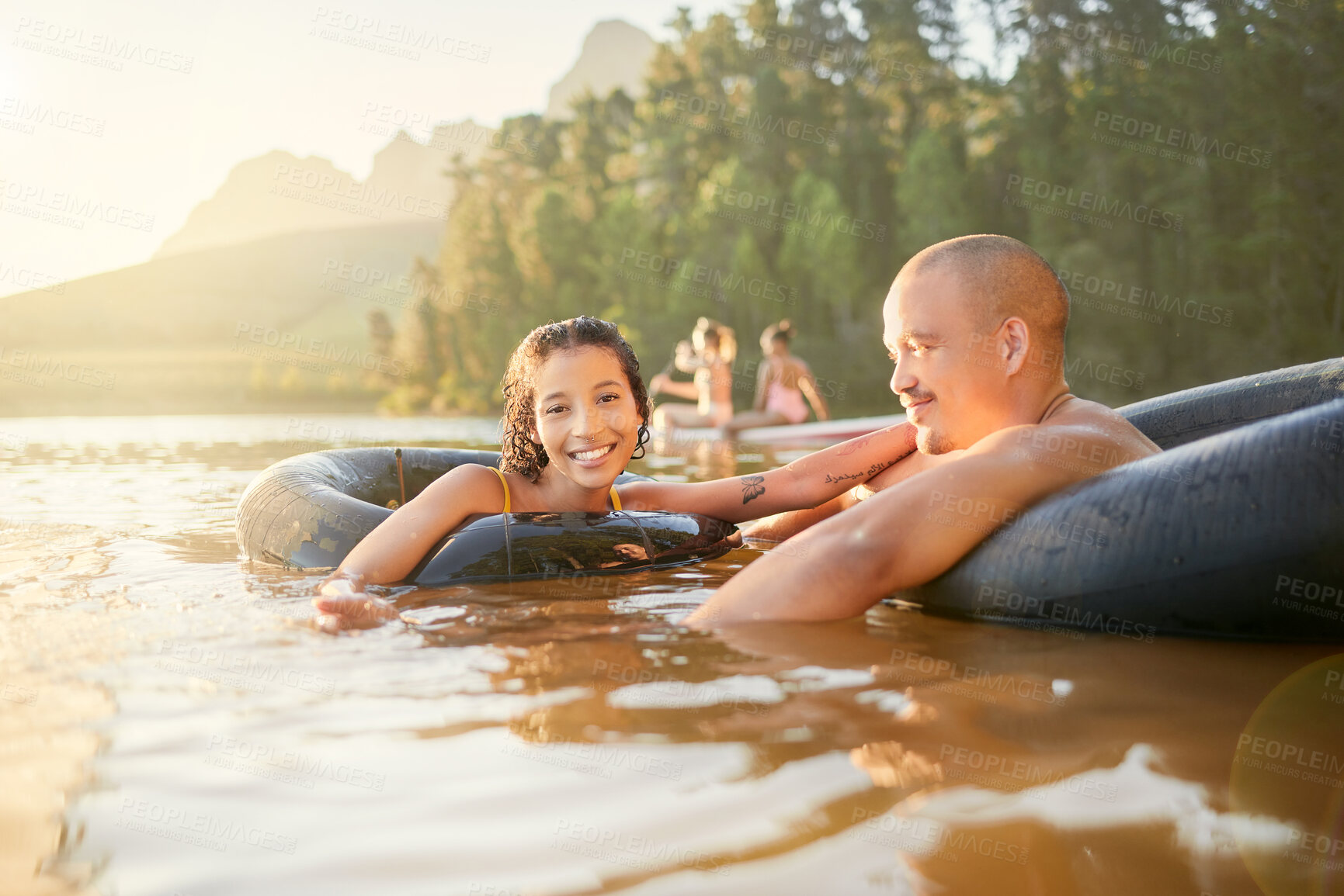 Buy stock photo Portrait, tube or happy couple in lake to relax on holiday travel, vacation, or weekend together. Smile, float or woman swimming with freedom, joy or romantic man in river water, dam or calm nature