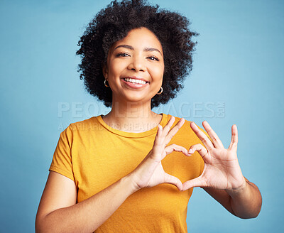 Buy stock photo Happy, portrait and woman with a heart shape for romance, care or flirting expression in a studio. Happiness, smile and young female model with love gesture, emoji or sign isolated by blue background