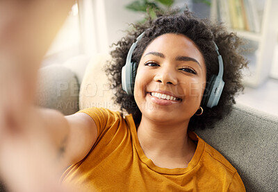 Buy stock photo Shot of a young woman taking a selfie while listening to music at home