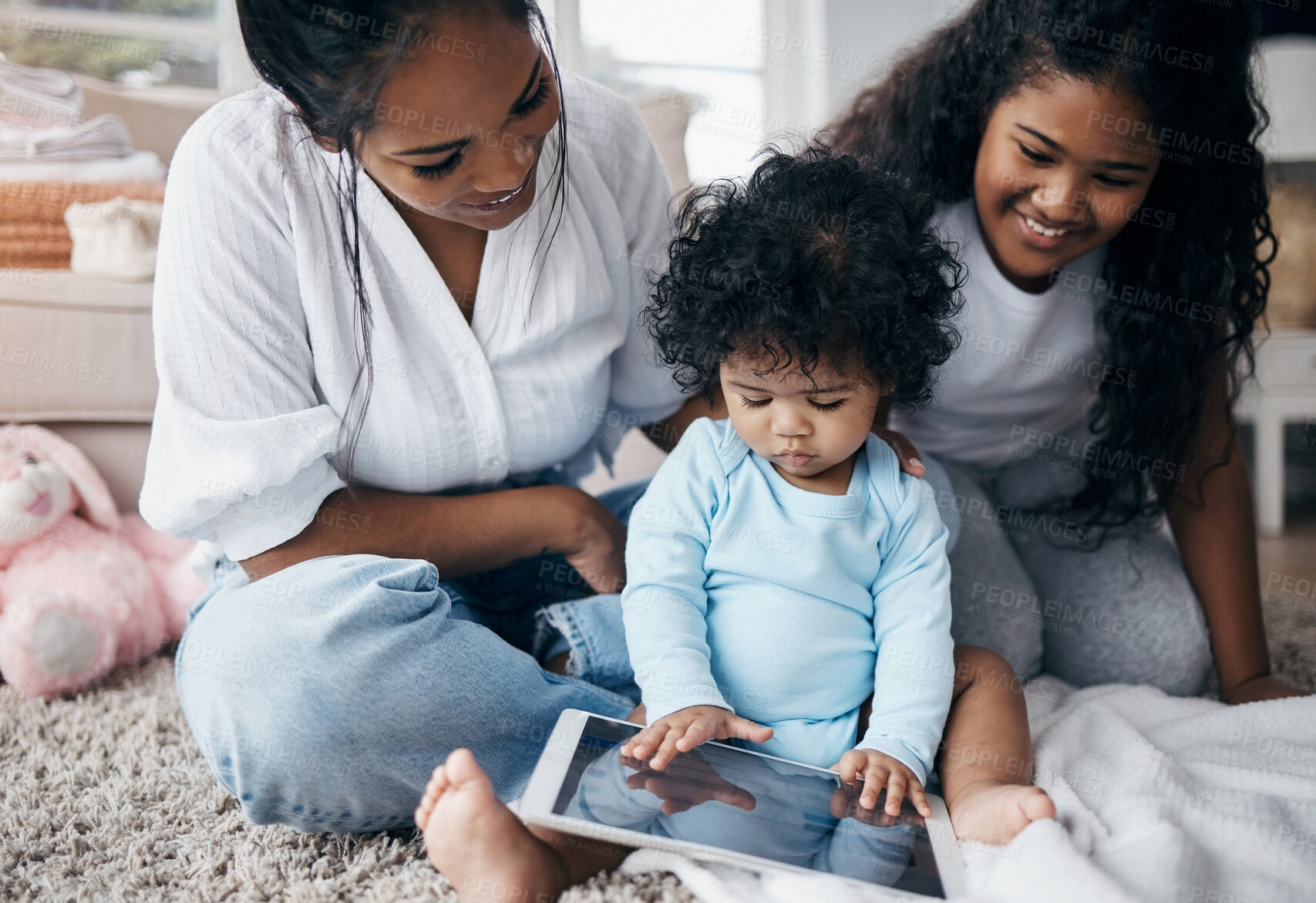 Buy stock photo Shot of an attractive young woman sitting on the living room floor with her children and using a digital tablet