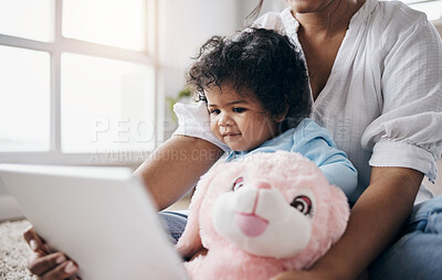 Buy stock photo Shot of an adorable little girl sitting at home and bonding with her mother while using a digital tablet