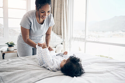 Buy stock photo Shot of a young mother changing her baby girl at home
