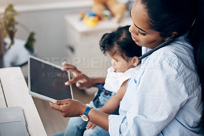 Buy stock photo Shot of a young mother caring for her baby girl while working from home