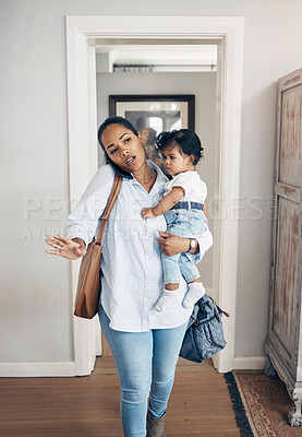 Buy stock photo Shot of a young woman looking annoyed while talking on a cellphone and carrying her daughter at home