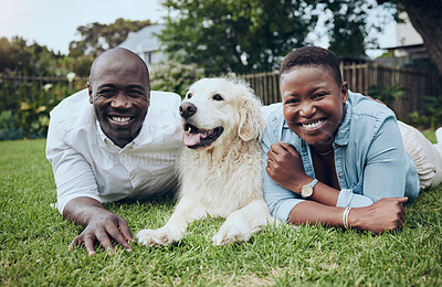 Buy stock photo Shot of a young couple lying on the grass with their dog in their garden at home