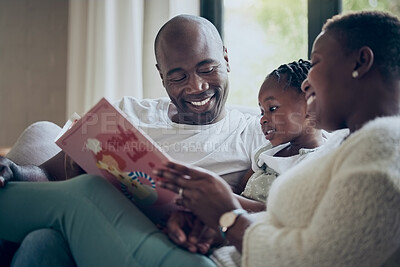 Buy stock photo Shot of a young family reading a book together at home