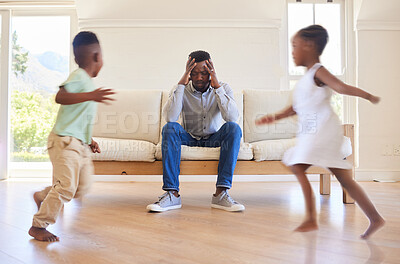 Buy stock photo Shot of a young father looking stressed while his kids play around him