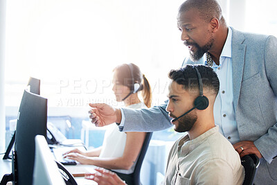 Buy stock photo Shot of a mature businessman standing and helping his call centre agents in the office