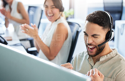 Buy stock photo Shot of a handsome young call centre agent sitting in the office and celebrating a success while using his computer