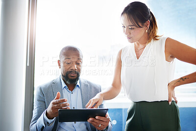Buy stock photo Shot of two businesspeople having a discussion in the office while using a digital tablet