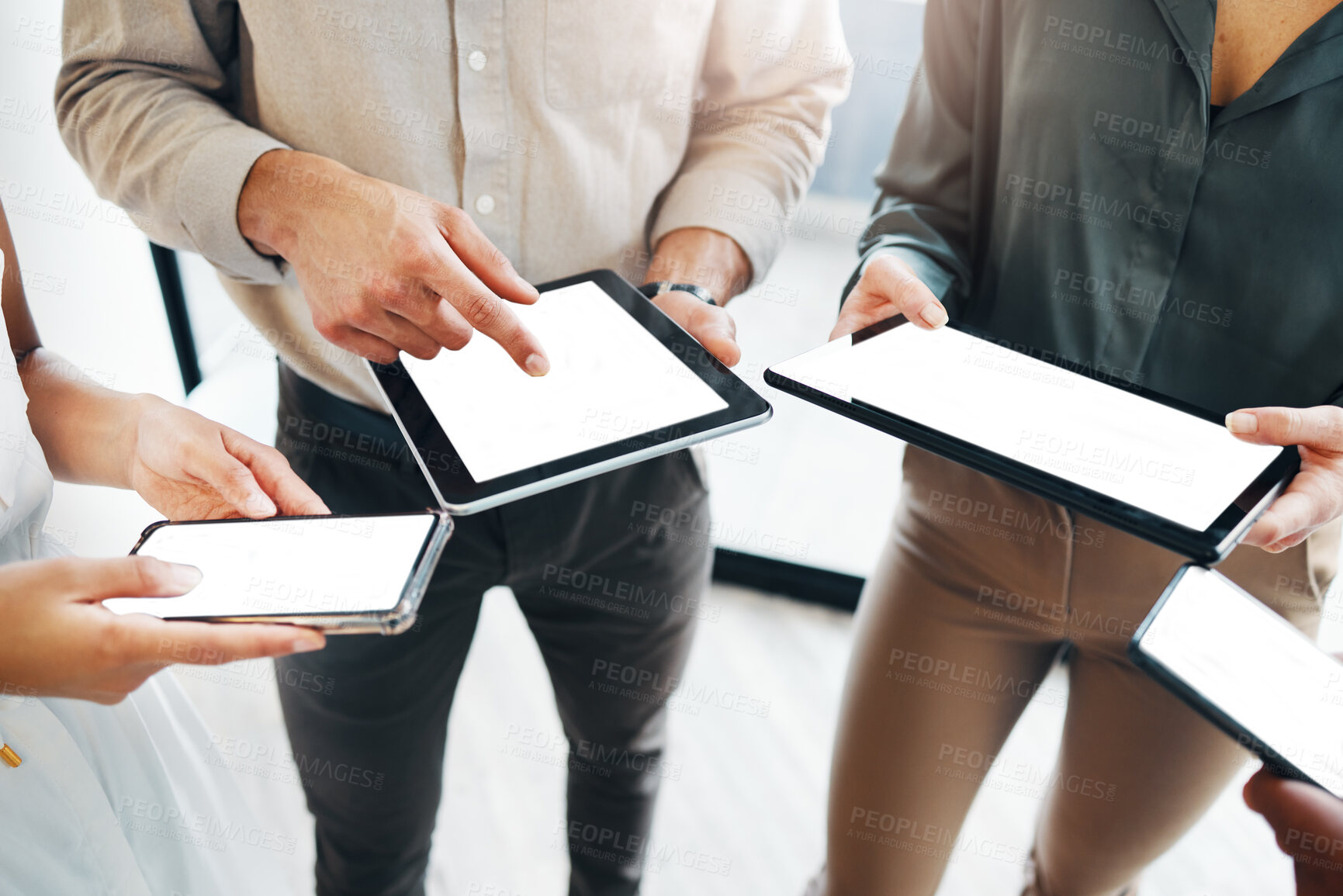 Buy stock photo Cropped shot of an unrecognisable group of businesspeople standing together and using technology