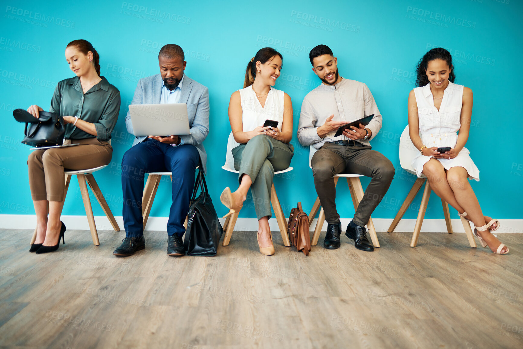 Buy stock photo Full length shot of a diverse group of businesspeople sitting together in the office and using technology