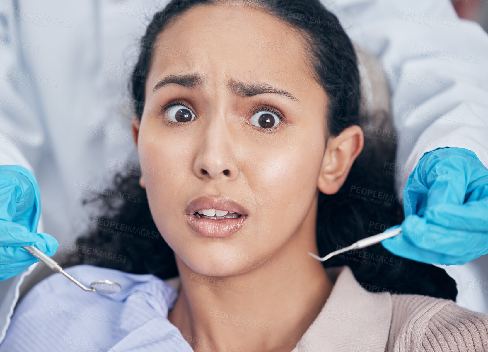 Buy stock photo Shot of a young woman looking afraid at her dentists office