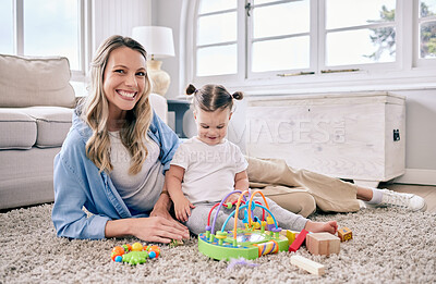Buy stock photo Shot of a mom sitting with her daughter while she plays with her toys