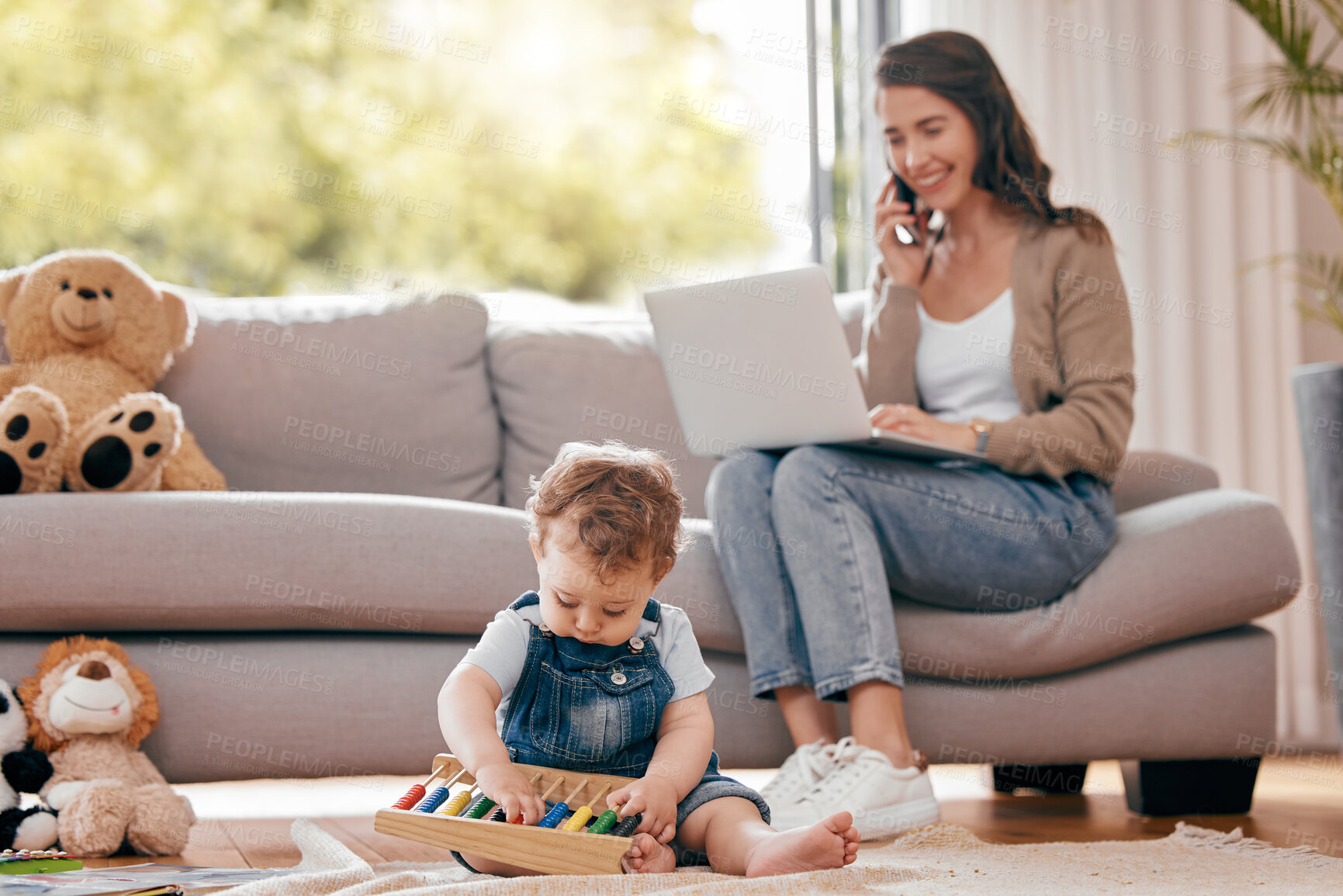 Buy stock photo Shot of a mother using a laptop while her son plays at home