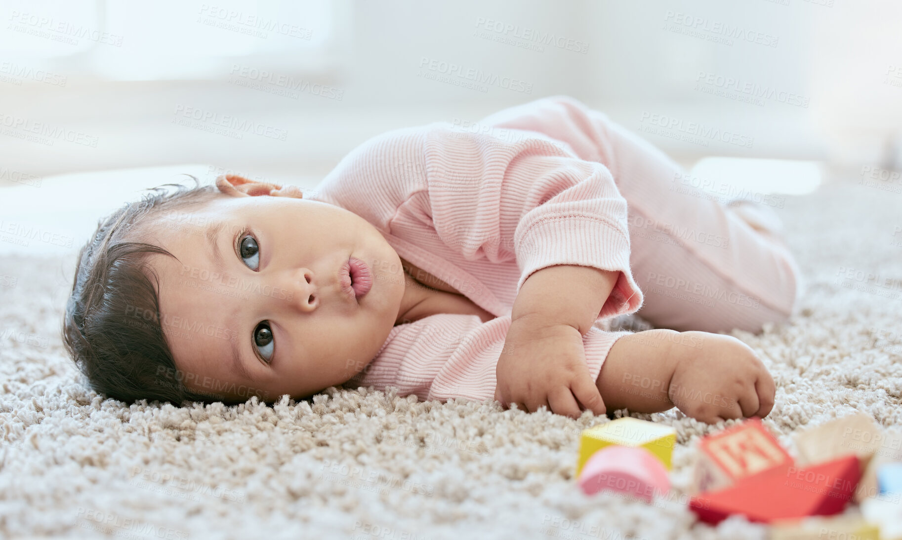 Buy stock photo Baby, face and relax on carpet in home with building blocks for cognitive development, playing and curious for learning. Infant, child or resting on floor with wooden toys for coordination in nursery