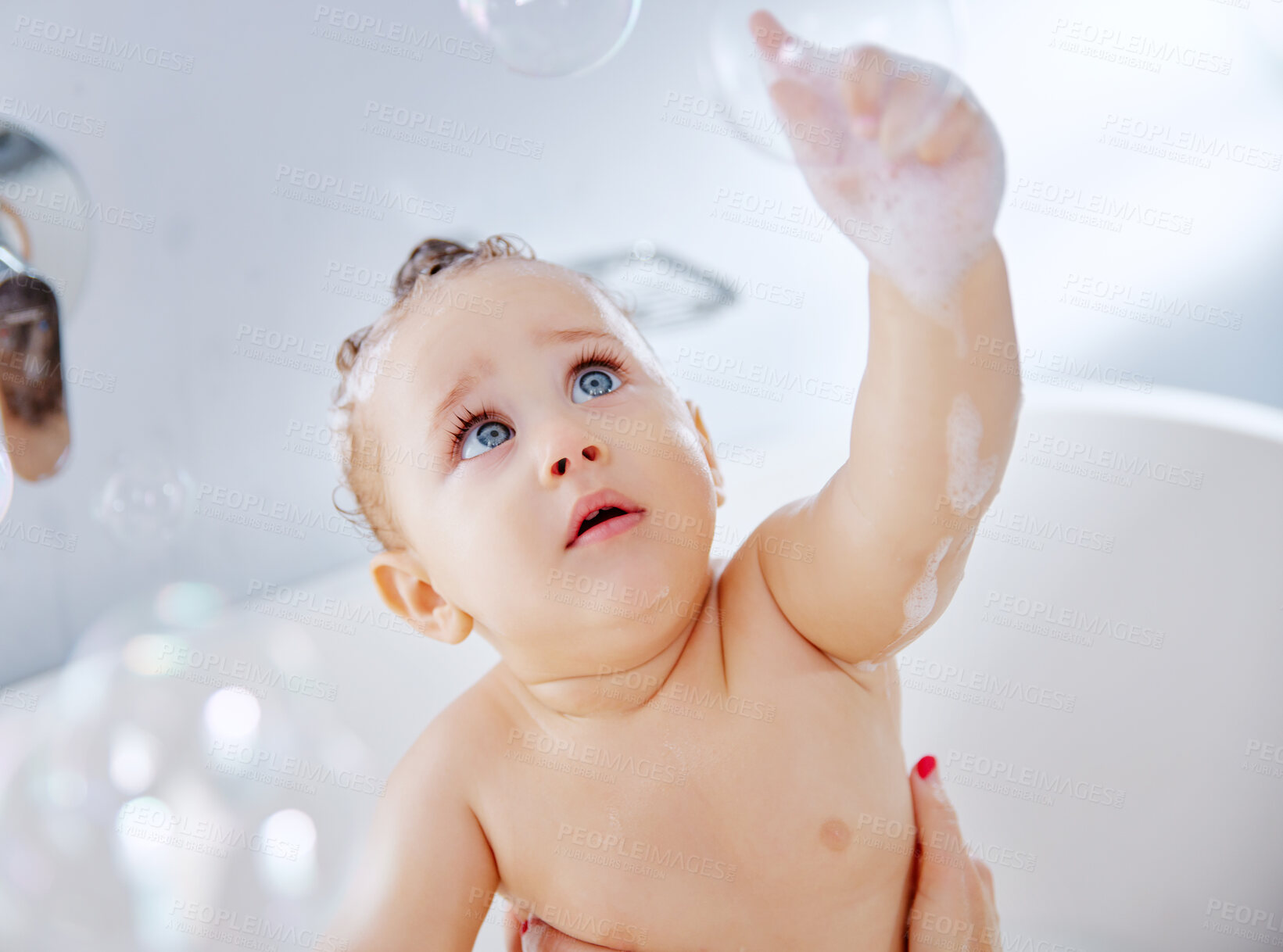 Buy stock photo Baby, face and popping with bubbles in bath for playful in tub for hygiene, cleaning or wash at home. Cute little child, newborn or adorable kid enjoying fun in soapy bathtub with water at house