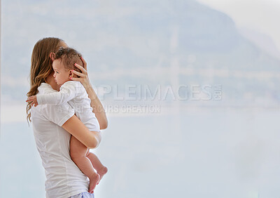 Buy stock photo Shot of an young woman standing at home and carrying her baby