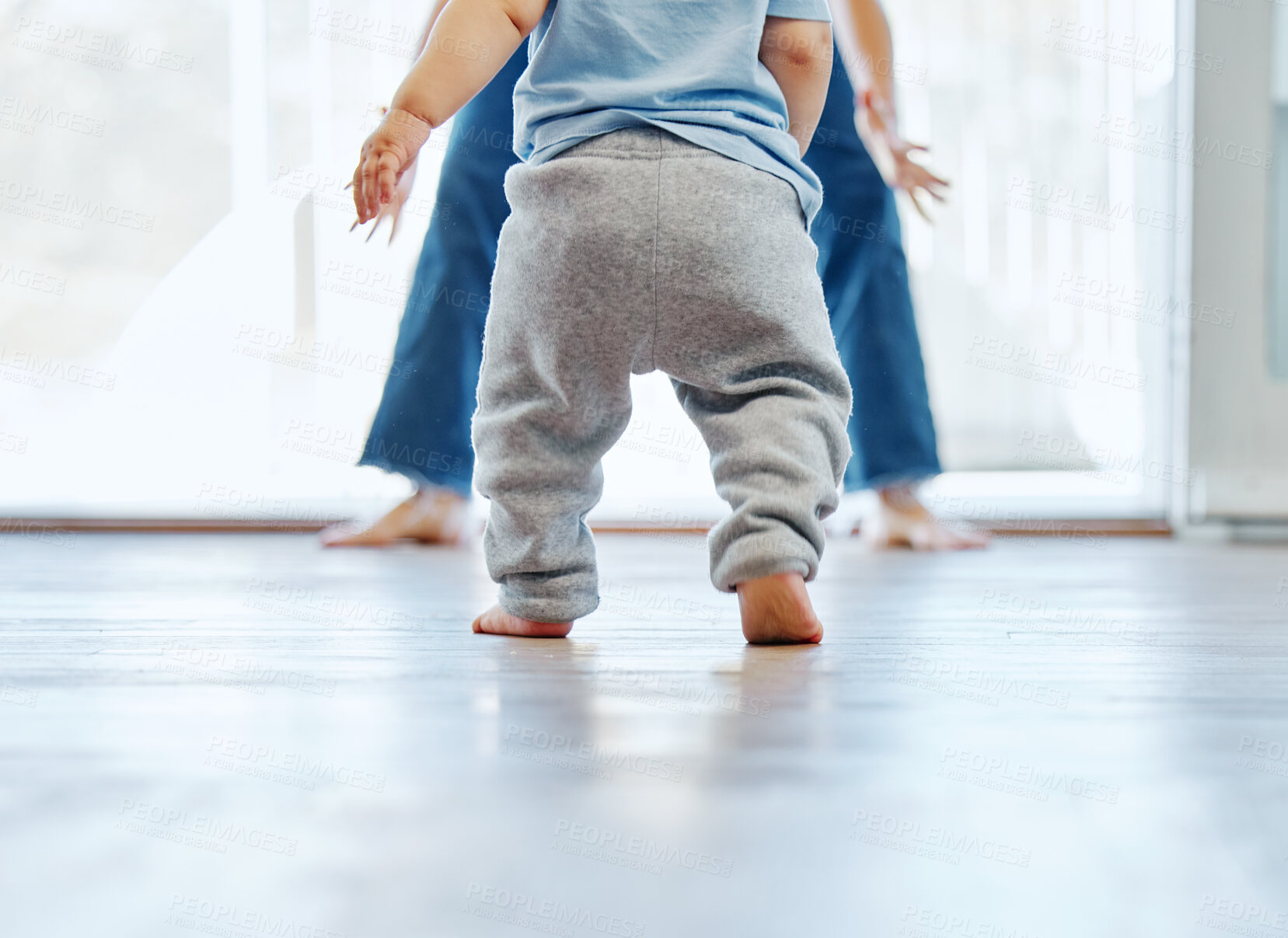 Buy stock photo Cropped shot of an unrecognizable little boy learning to walk with the help of his mother at home