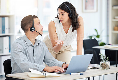 Buy stock photo Shot of two call centre agents working together on a laptop in an office