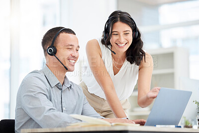 Buy stock photo Shot of two call centre agents working together on a laptop in an office