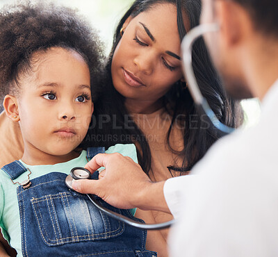 Buy stock photo Shot of a little girl sitting on her mother's lap while being examined by her doctor