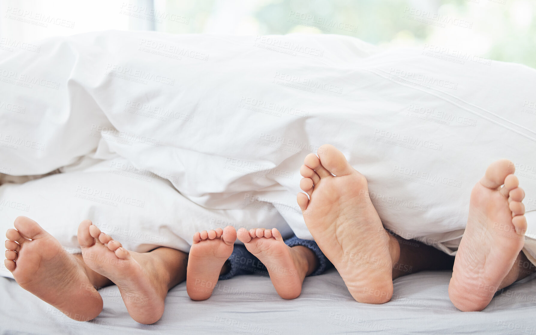Buy stock photo Cropped shot of a little girl lying between her mother and father on their bed