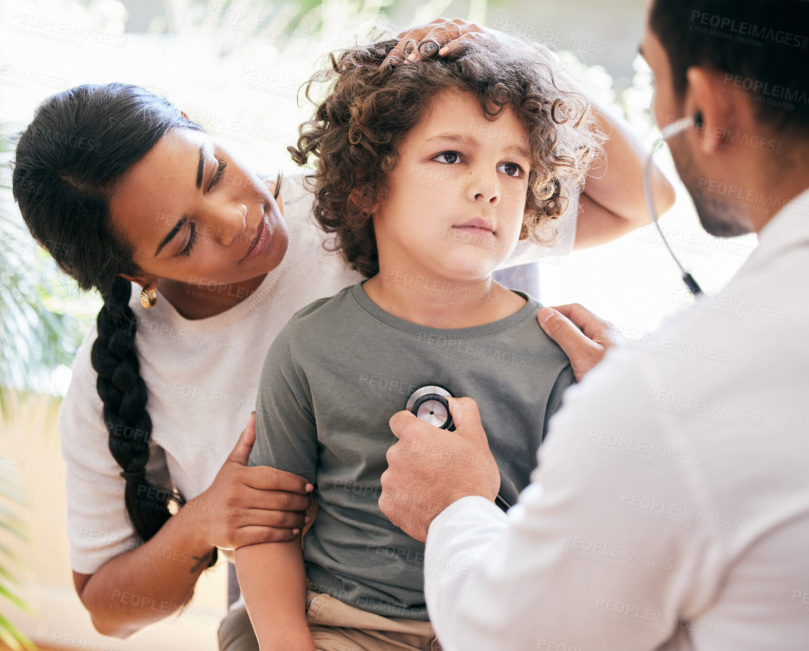 Buy stock photo Shot of a little boy being examined by an unrecognizable doctor while his mother holds him