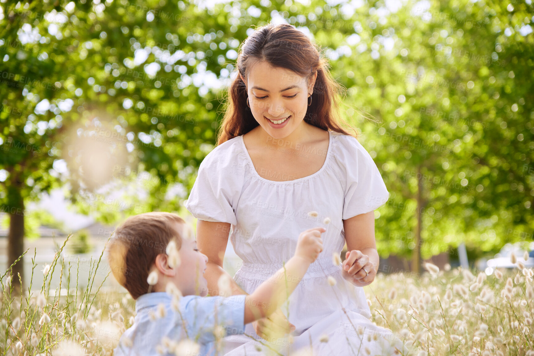 Buy stock photo Mother, boy and flowers in meadow to relax on holiday, love and plants for bonding in outdoor. Mommy, son and happiness in field or travel to countryside, peace and freedom on vacation for wellness