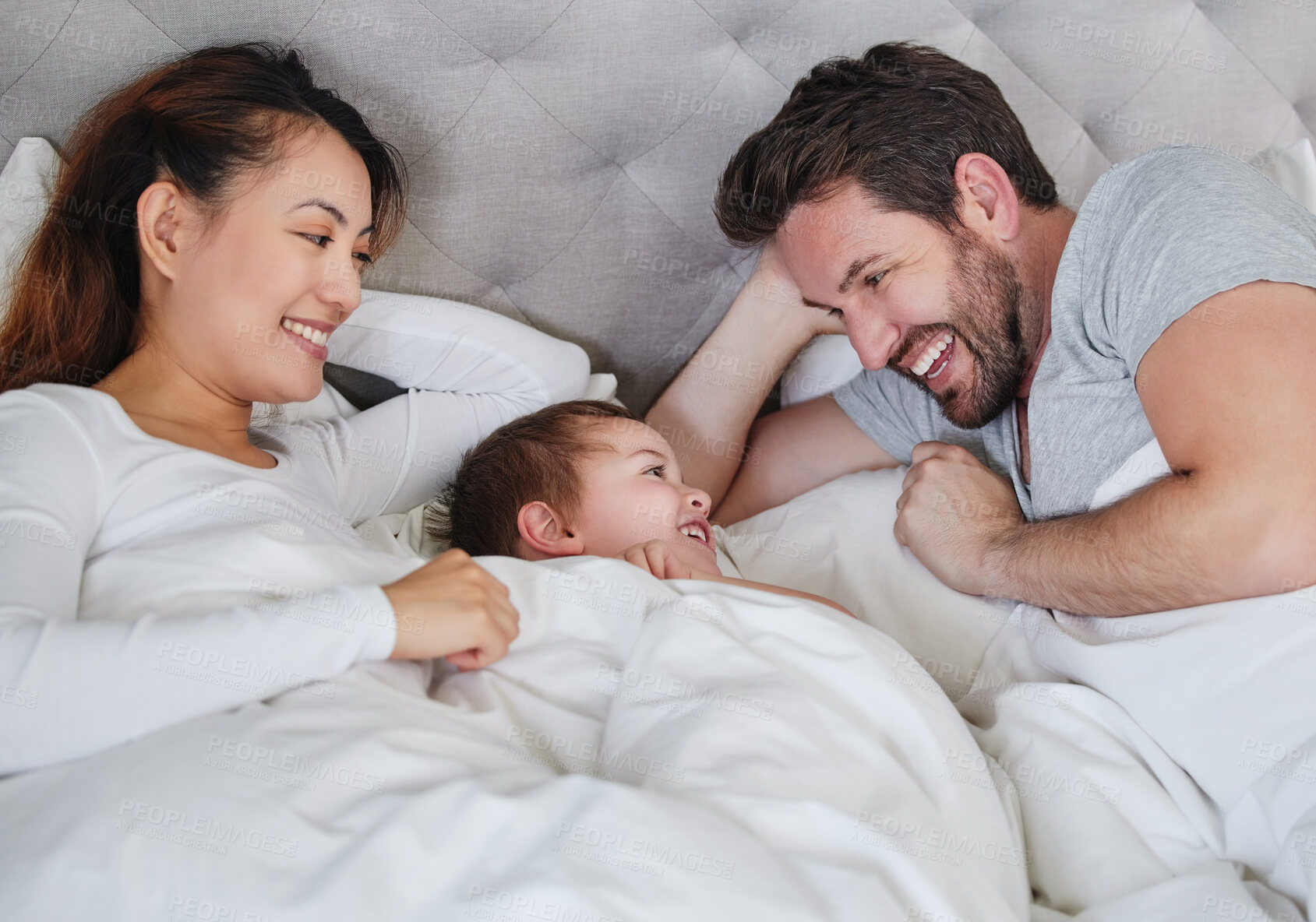 Buy stock photo Mother, son and father in bedroom, smile and bonding with love, man and woman with care for boy in home. Mom, dad and kid together on bed, happiness and relax in weekend, parents and child in house