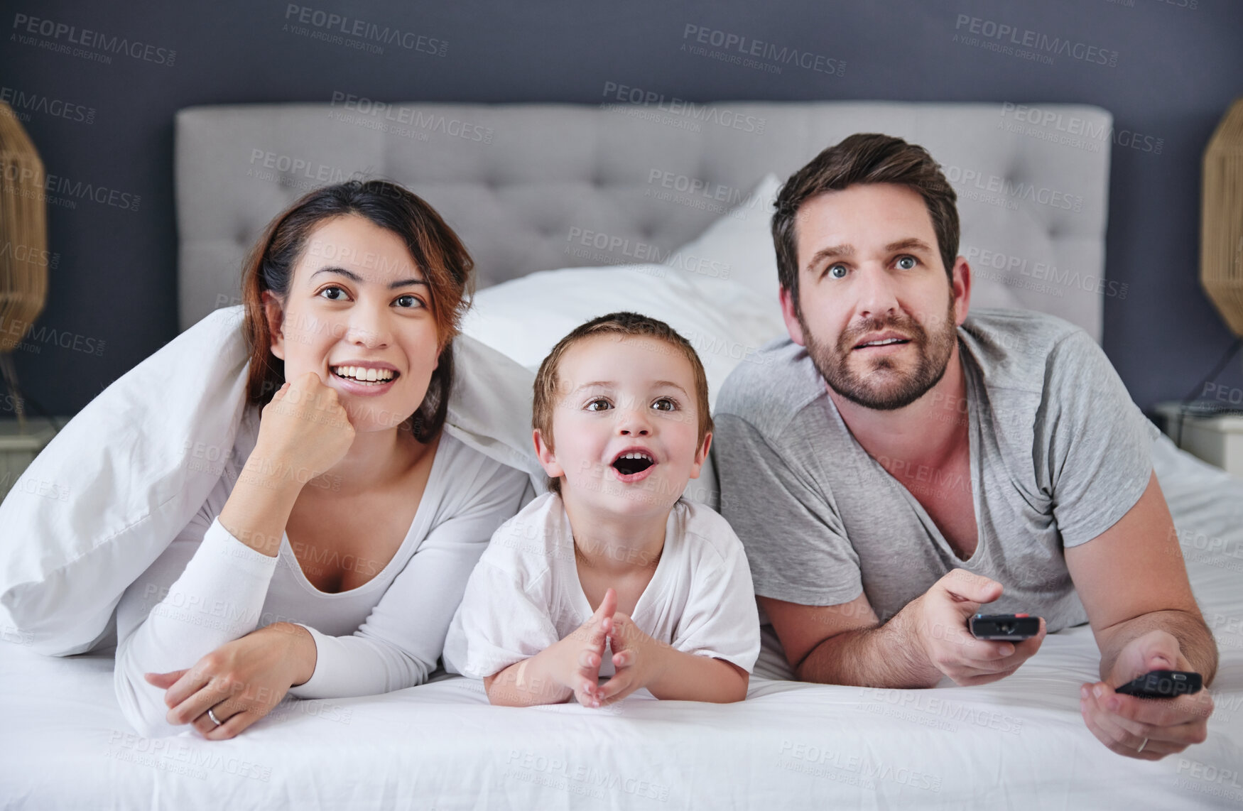 Buy stock photo Watch, son and family in bedroom, remote and bonding with love, man and woman with movies for boy in home. Mom, dad and kid together on bed, happiness and television to relax, parents and child