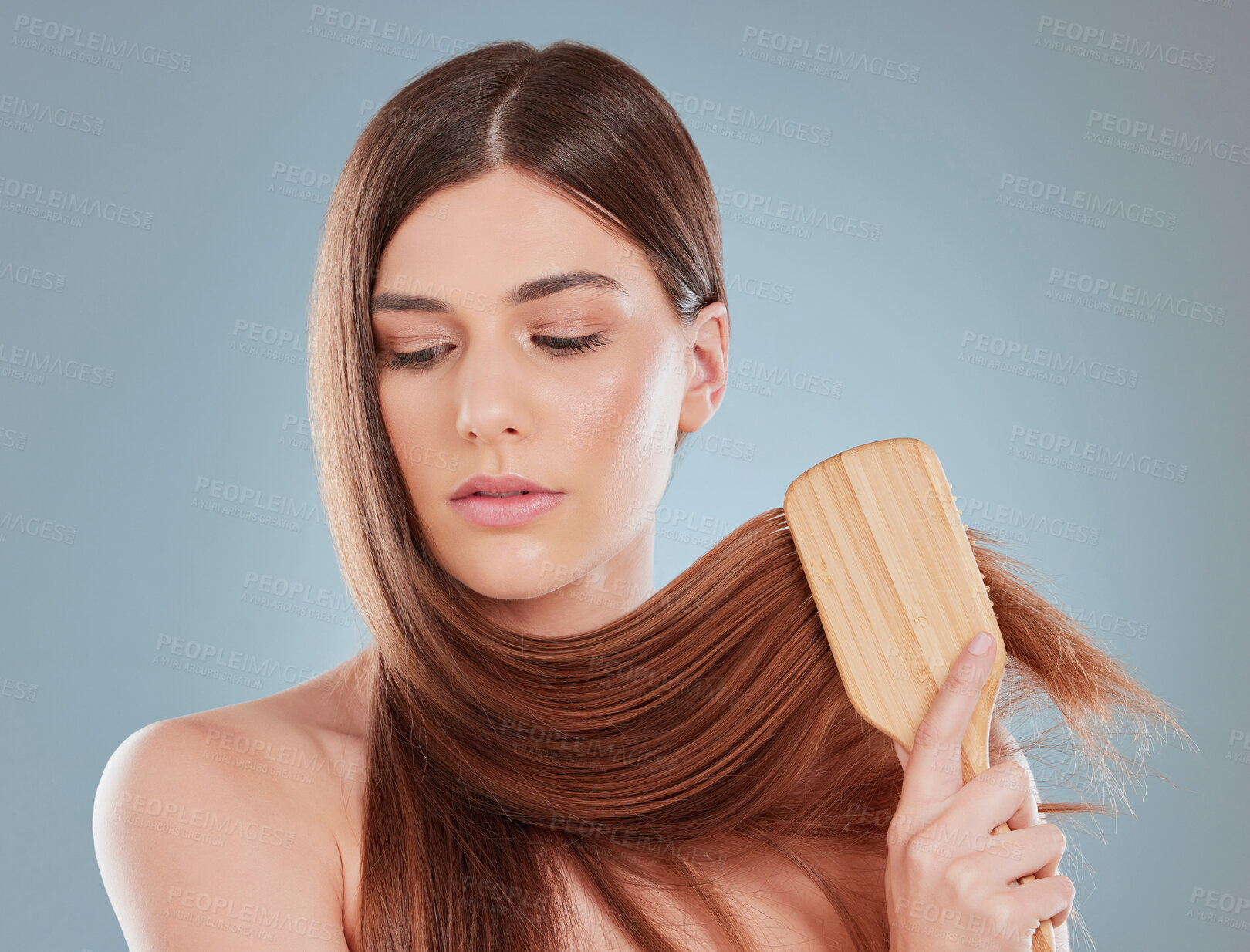 Buy stock photo Studio shot of a young woman brushing her hair
