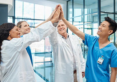 Buy stock photo Shot of a group of doctors putting their hands together at a modern hospital