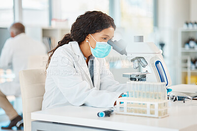 Buy stock photo Shot of a young scientist using a microscope in a lab