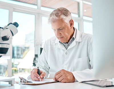 Buy stock photo Shot of a senior scientist writing notes in a lab