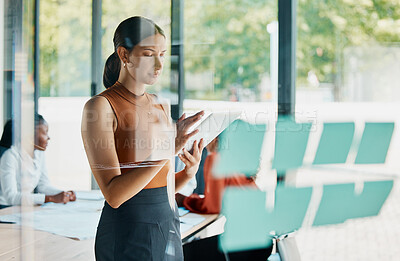 Buy stock photo Cropped shot of an attractive young businesswoman using her tablet while standing in the boardroom
