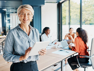 Buy stock photo Cropped portrait of an attractive mature businesswoman using her tablet while standing in the boardroom