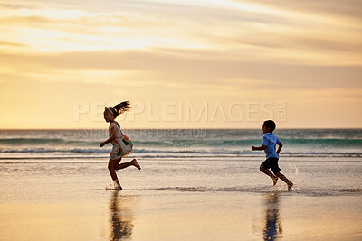 Buy stock photo Shot of a little boy and girl playing chase at the beach