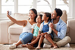 Happy young family taking a family selfie while relaxing and spending family time together at home
