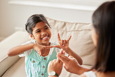 Buy stock photo Sign language, communication and child with her mother in the living room of their family home. Happy, smile and girl kid speaking with her hands to her deaf mom to communicate in their modern house.