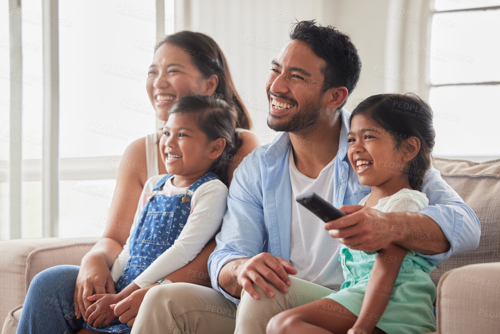 Buy stock photo Parents, girl and children for watching tv on couch with remote, hug and happy for show in family home. Father, mother and daughter kids with streaming, subscription and relax with movie in Indonesia