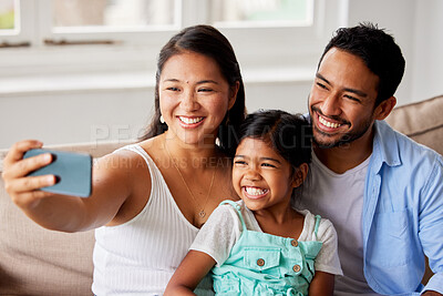 Buy stock photo Cheerful young family taking a selfie with their daughter while bonding on the couch at home