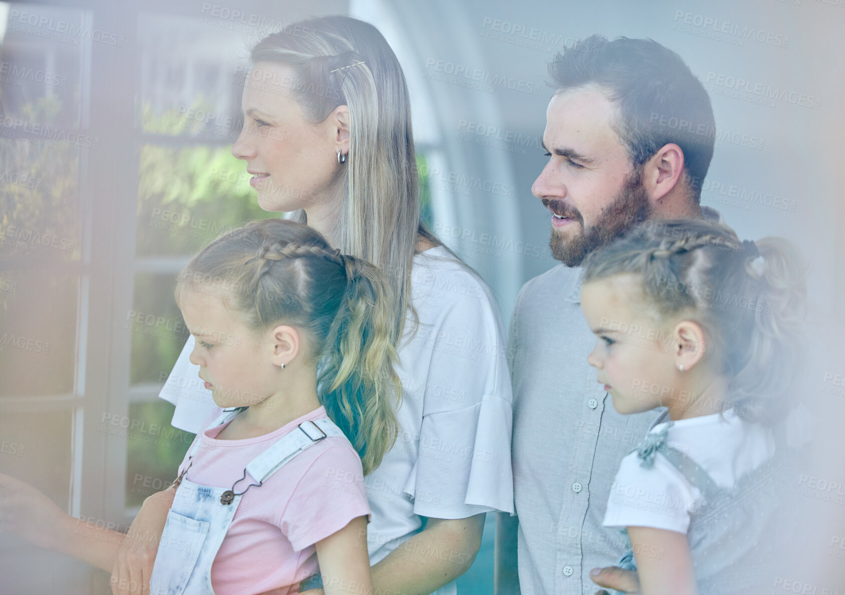 Buy stock photo Shot of a young family looking out of their window from their lounge at home