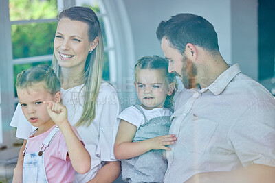 Buy stock photo Shot of a young family looking out of their window from their lounge at home