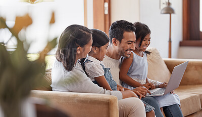Buy stock photo Cropped shot of an affectionate young family of four using a laptop while sitting on the sofa at home