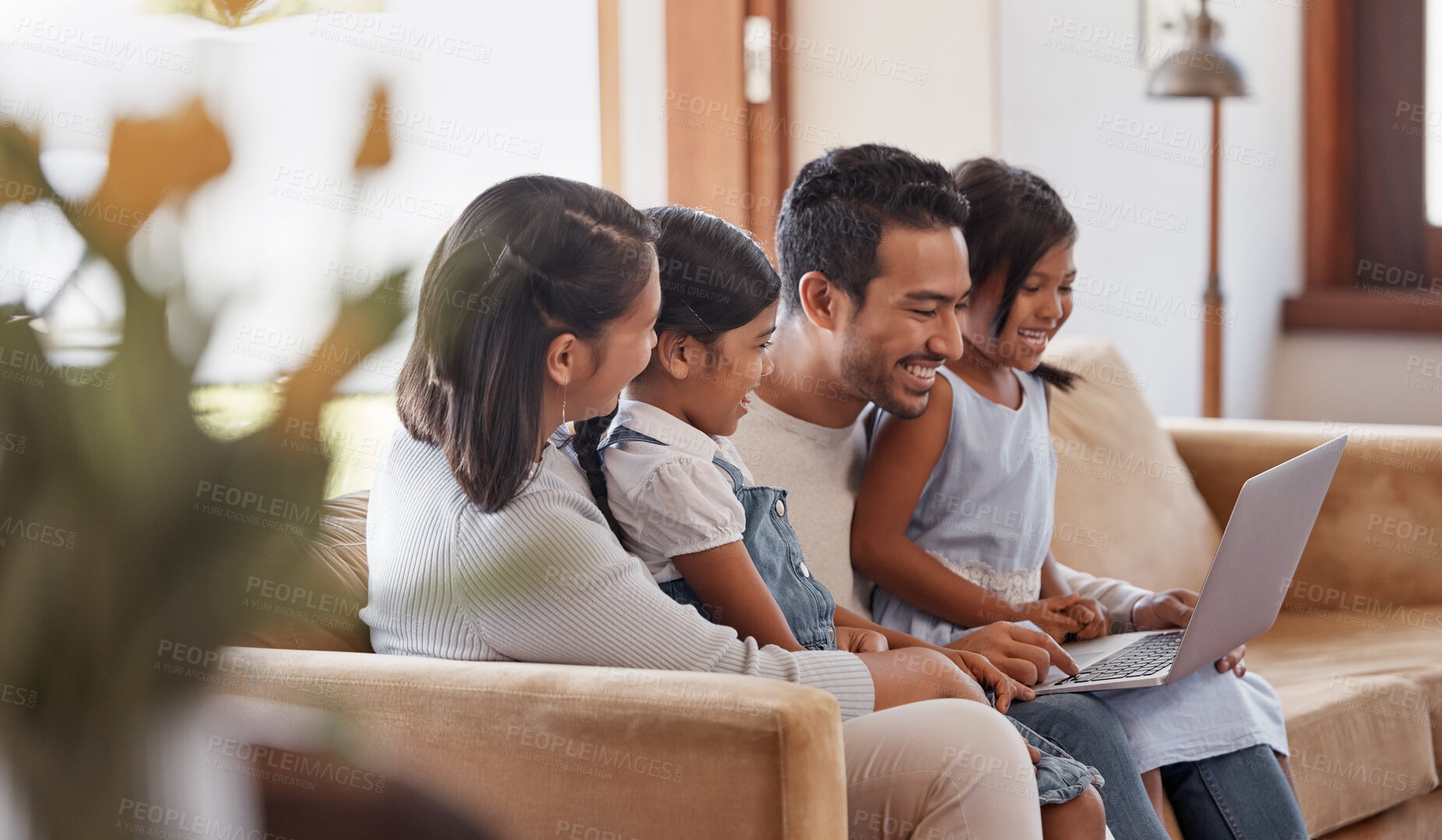Buy stock photo Cropped shot of an affectionate young family of four using a laptop while sitting on the sofa at home
