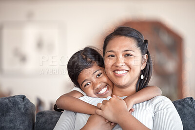 Buy stock photo Cropped portrait of an adorable little girl hugging her mother from behind while in the living room at home