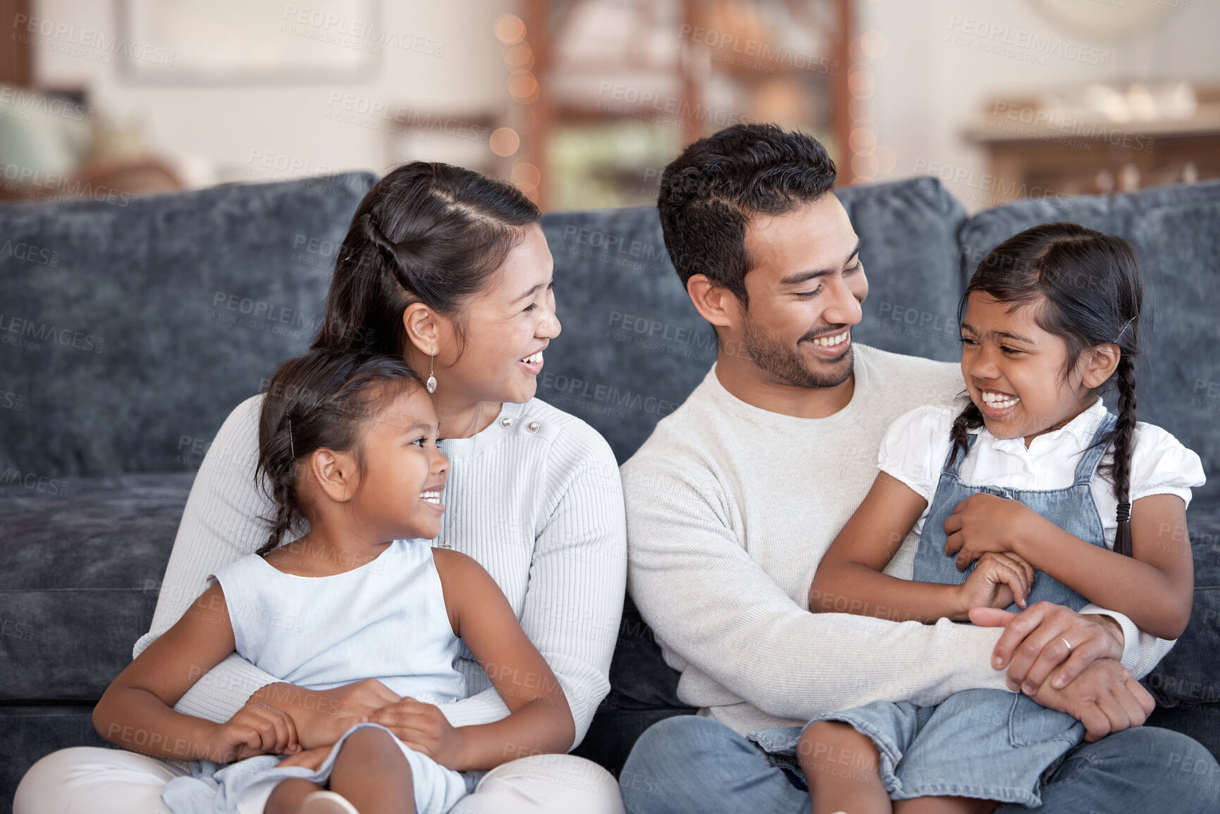 Buy stock photo Asian parents, children and laugh on sofa with hug, care and bonding with love, connection and relax together. Father, mother and daughter kids with funny conversation at family house in home