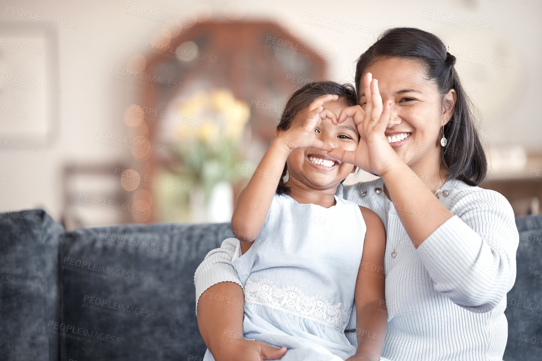 Buy stock photo Asian mom, girl and heart hands on sofa for hug, care or bonding with love, connection or relax with emoji. Woman, mother and daughter with sign, icon or symbol for kindness at family home in Jakarta