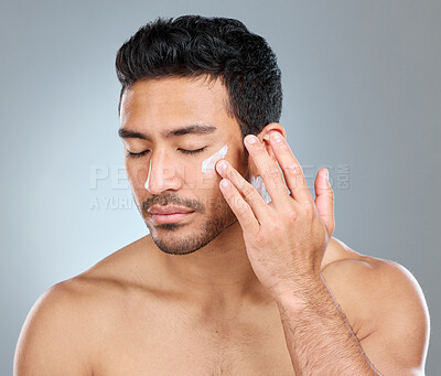 Buy stock photo Man, eyes closed and cream in studio for skincare, hydration and skin tone with dermatology or cosmetology. Male person, lotion and sunscreen on gray background for facial care, grooming and calm.